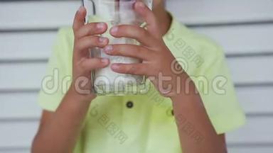 小可爱的男孩早上在喝牛奶。 可爱的白种人儿童喝着杯子里的牛奶。 男孩喝牛奶